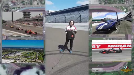 Person in racing jacket standing at Indianapolis Motor Speedway with race cars